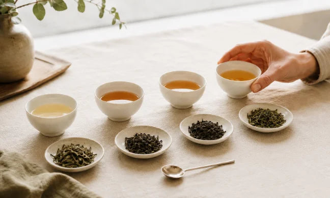 Four brewed teas and matching loose leaves arranged for tasting