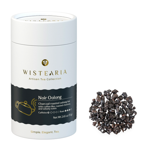 Wistearia Noir Oolong Tea loose leaf tube beside a pile of dark rolled whole leaves