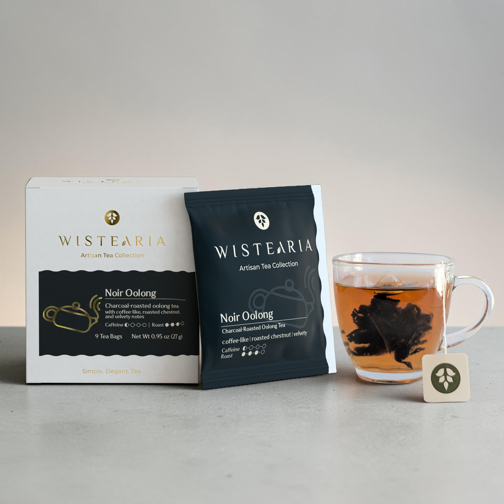 Noir Oolong Tea sachets box and sealed sachet wrapper beside a glass cup of freshly brewed tea