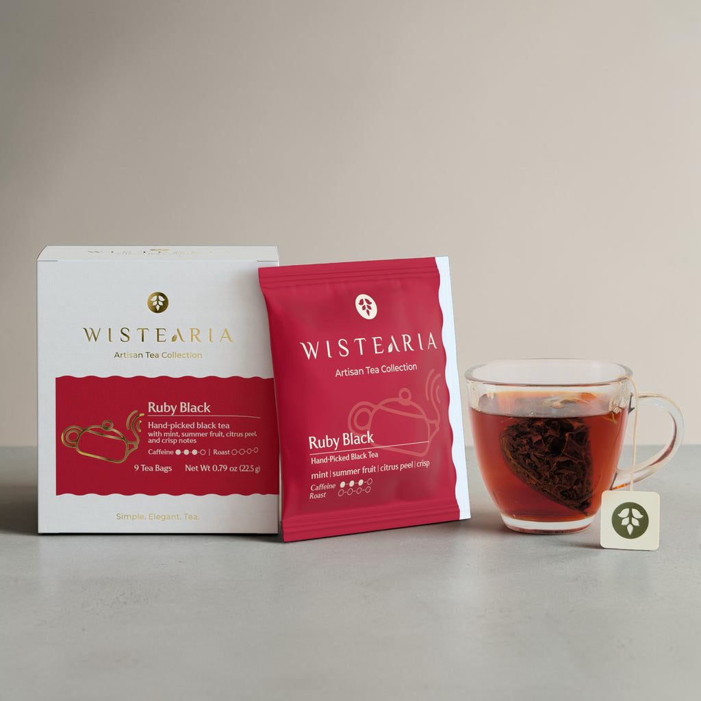 Ruby Black Tea sachets box and sealed sachet wrapper beside a glass cup of freshly brewed tea